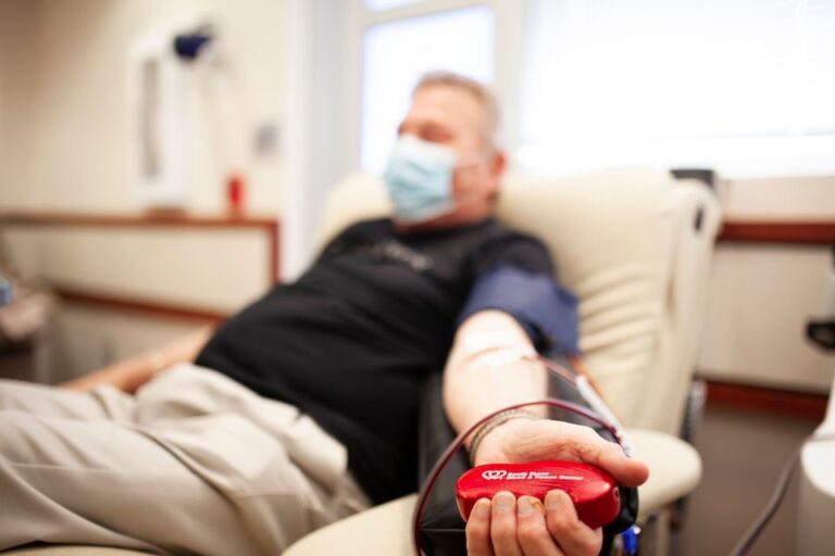 Male Blood Donor, holding South Texas Blood and Tissue squeeze ball symbolizing Blood Shortage .