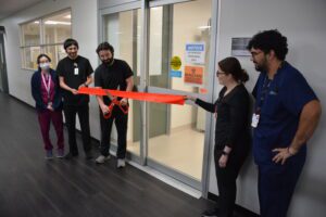 Medical staff cutting ribbon outside laboratory door