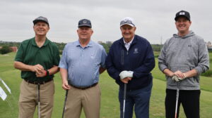 Four men holding golf clubs on course