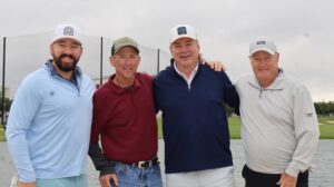 Four men posing at golf course by water