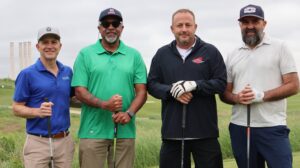 Four men holding golf clubs on course