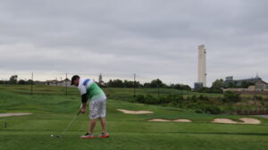 Golfer putting on green under cloudy sky