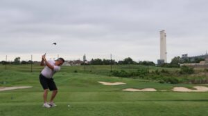 Man swinging golf club on green course