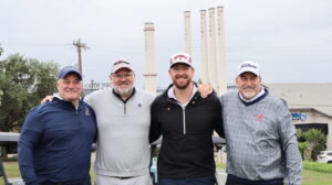 Four men in golf attire posing outdoors