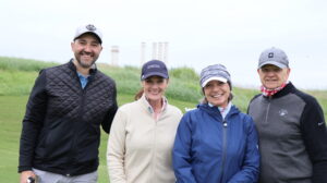 Four adults smiling on a golf course