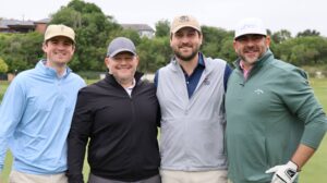 Four men posing on a golf course