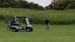 Golfers playing beside cart on green course
