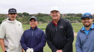 Four men posing on a golf course