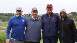 Four men posing together on a golf course