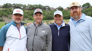 Four men posing together on a golf course