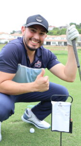 Smiling golfer kneeling on course giving thumbs up