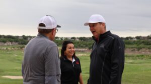 Three adults talking on a golf course