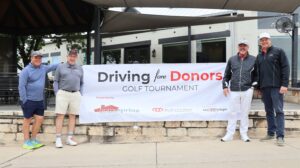 Four men at Driving fore Donors golf tournament banner