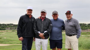 Four men posing on a golf course