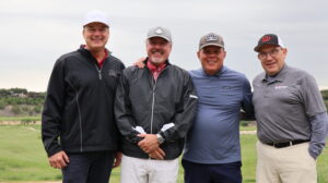 Four men posing on a golf course
