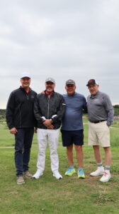 Four men posing on a golf course
