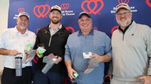 Four men holding gifts at charity event