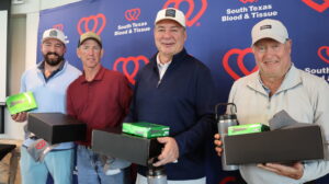 Four men holding golf prizes at event